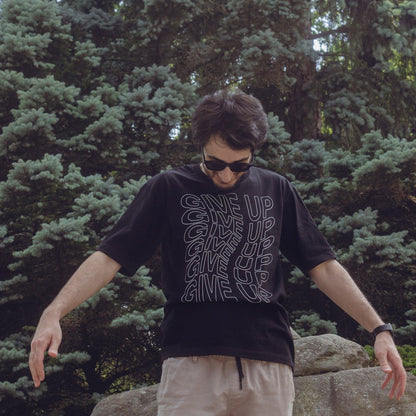 Male model wearing Give up oversized streetwear tshirt in front of a tree 