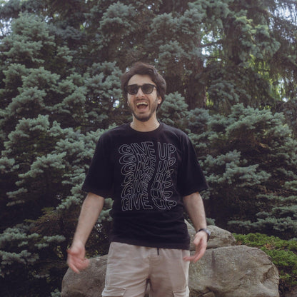 Male model wearing Give up oversized streetwear tshirt in front of a tree 